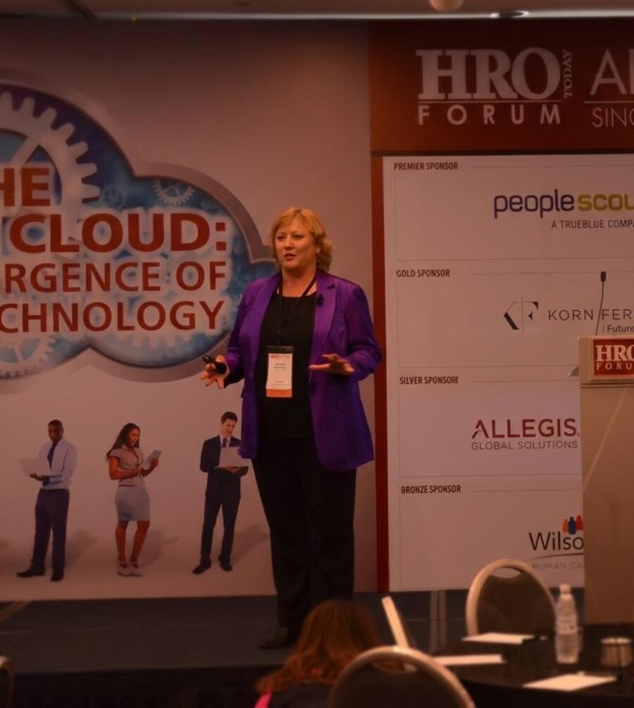 Andrea speaking on stage at a leadership forum